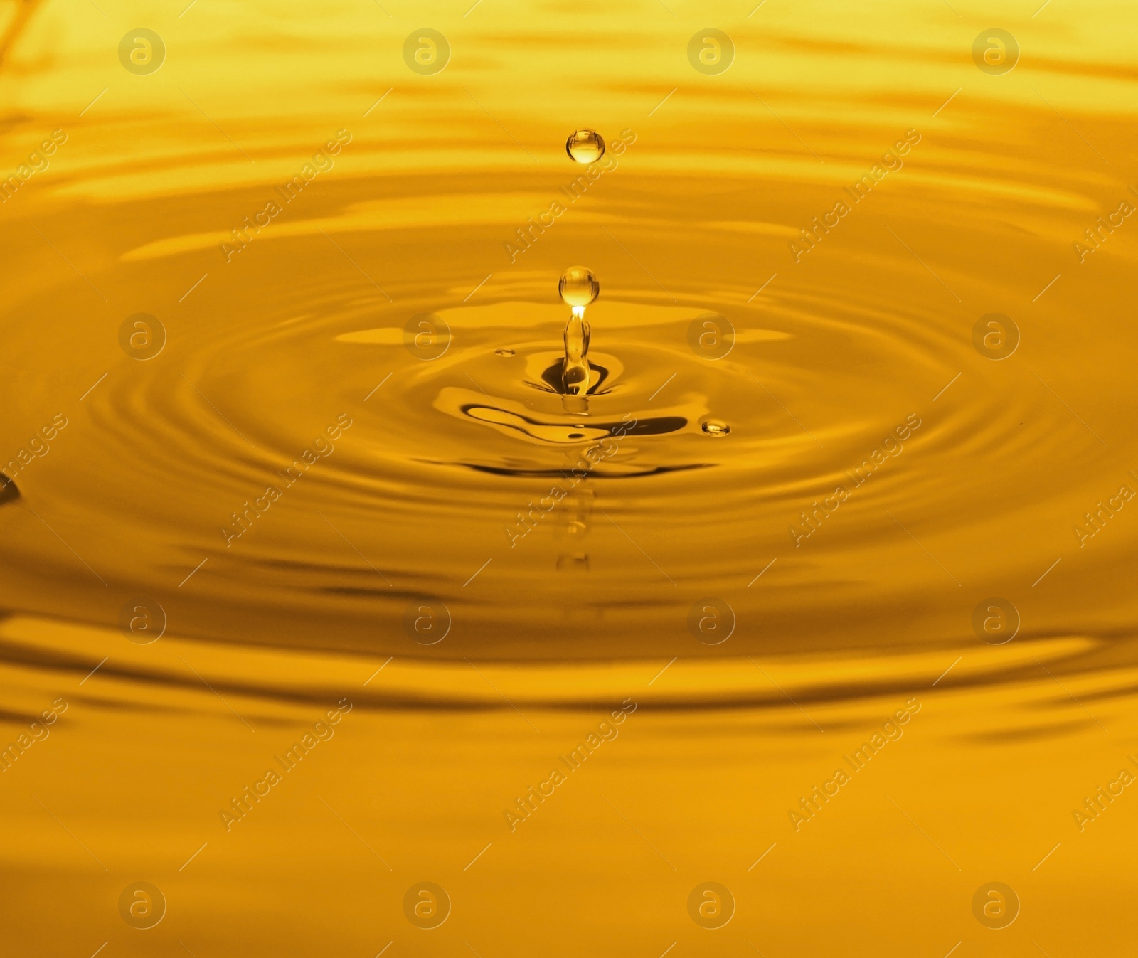 Image of Splash of golden oily liquid with drops as background, closeup
