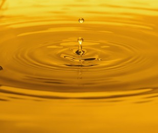 Splash of golden oily liquid with drops as background, closeup