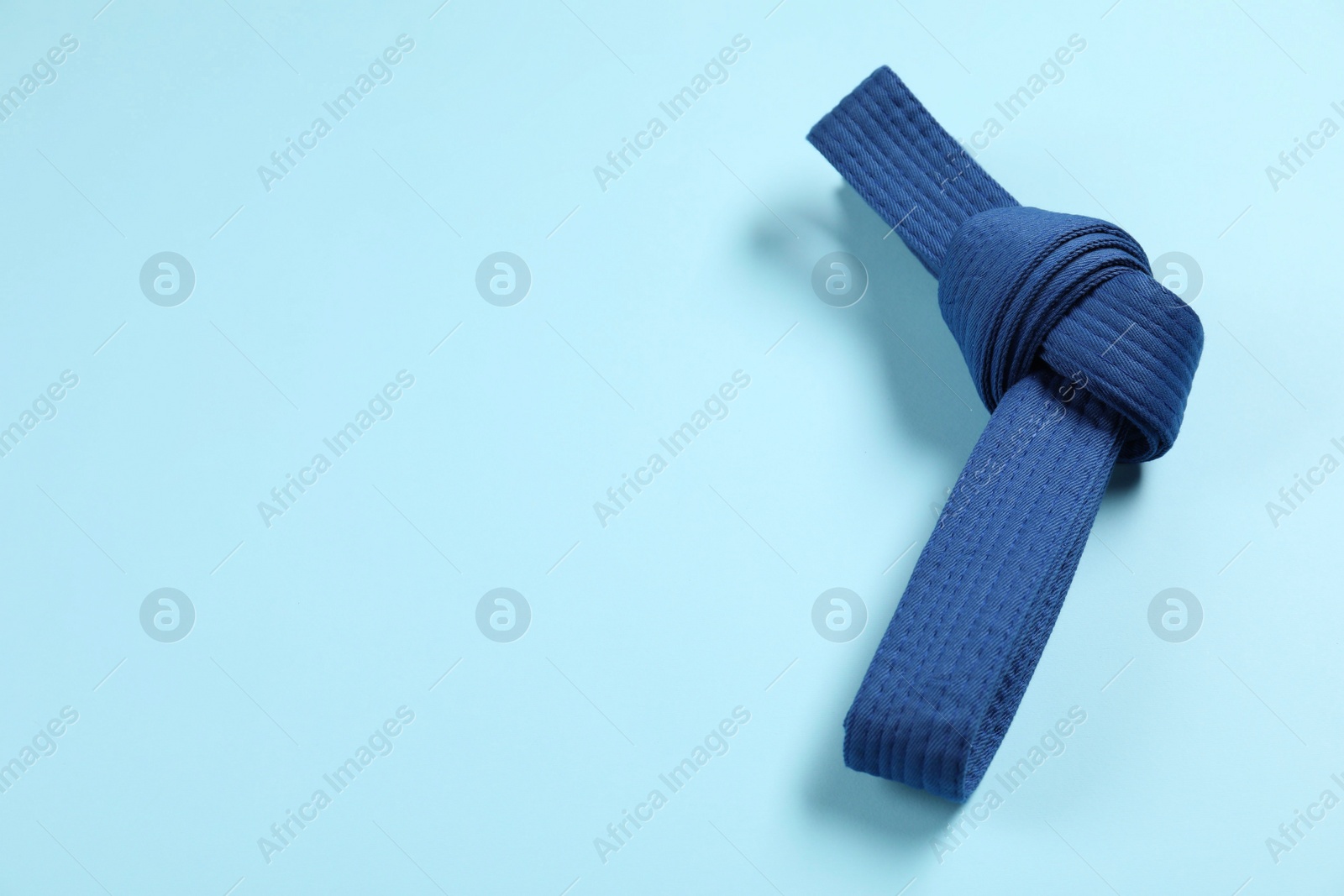 Photo of Karate belt on light blue background, top view. Space for text