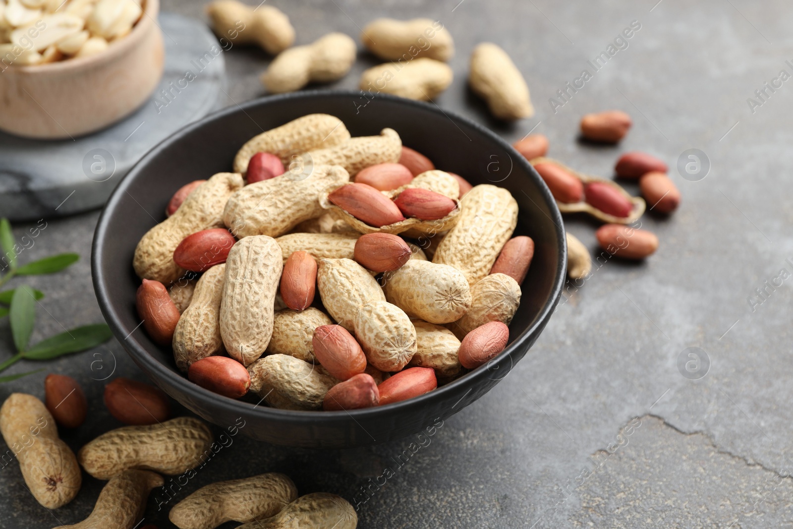 Photo of Fresh unpeeled peanuts in bowl on grey table