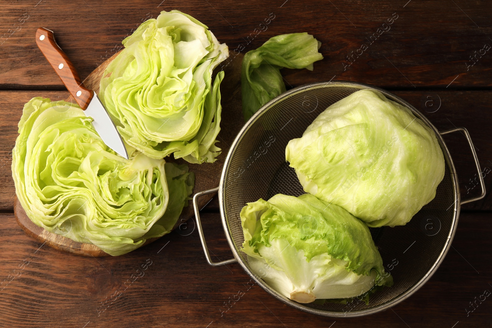 Photo of Fresh green whole and cut iceberg lettuce heads on wooden table, flat lay