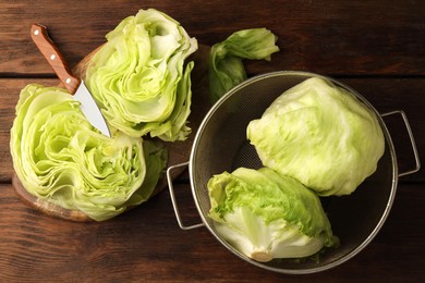 Photo of Fresh green whole and cut iceberg lettuce heads on wooden table, flat lay