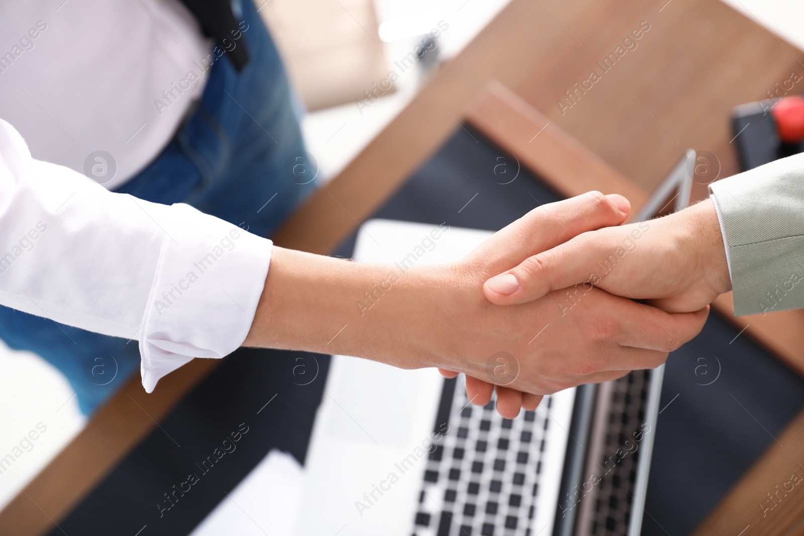 Photo of Business partners shaking hands at table after meeting in office, closeup