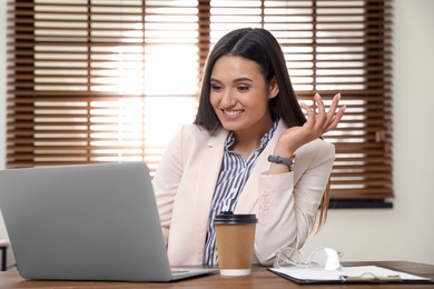 Young woman using video chat on laptop in home office