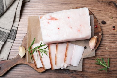 Photo of Pork fatback with rosemary, garlic and peppercorns on wooden table, flat lay