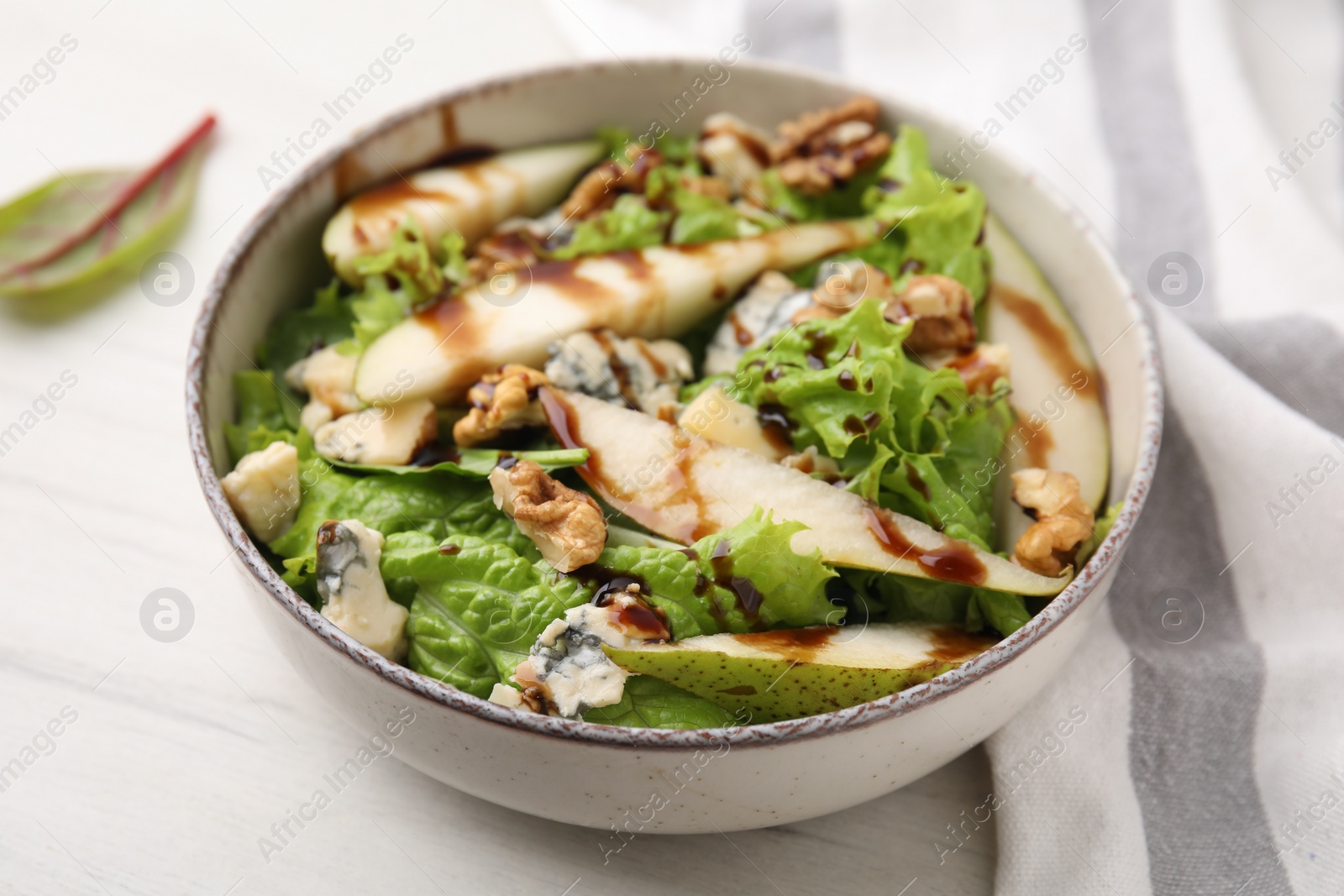 Photo of Delicious pear salad with sauce in bowl on light table, closeup