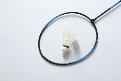 Photo of Feather badminton shuttlecock and racket on gray background, top view. Space for text