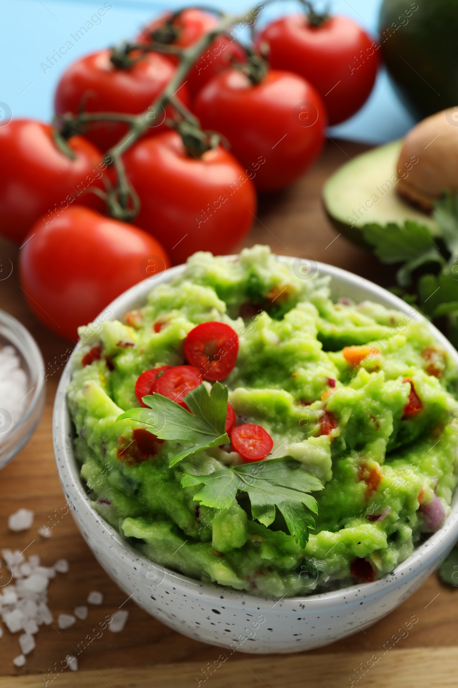 Photo of Delicious guacamole and ingredients on wooden board