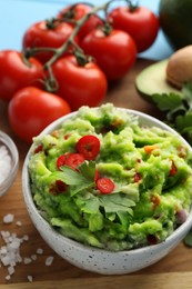 Photo of Delicious guacamole and ingredients on wooden board