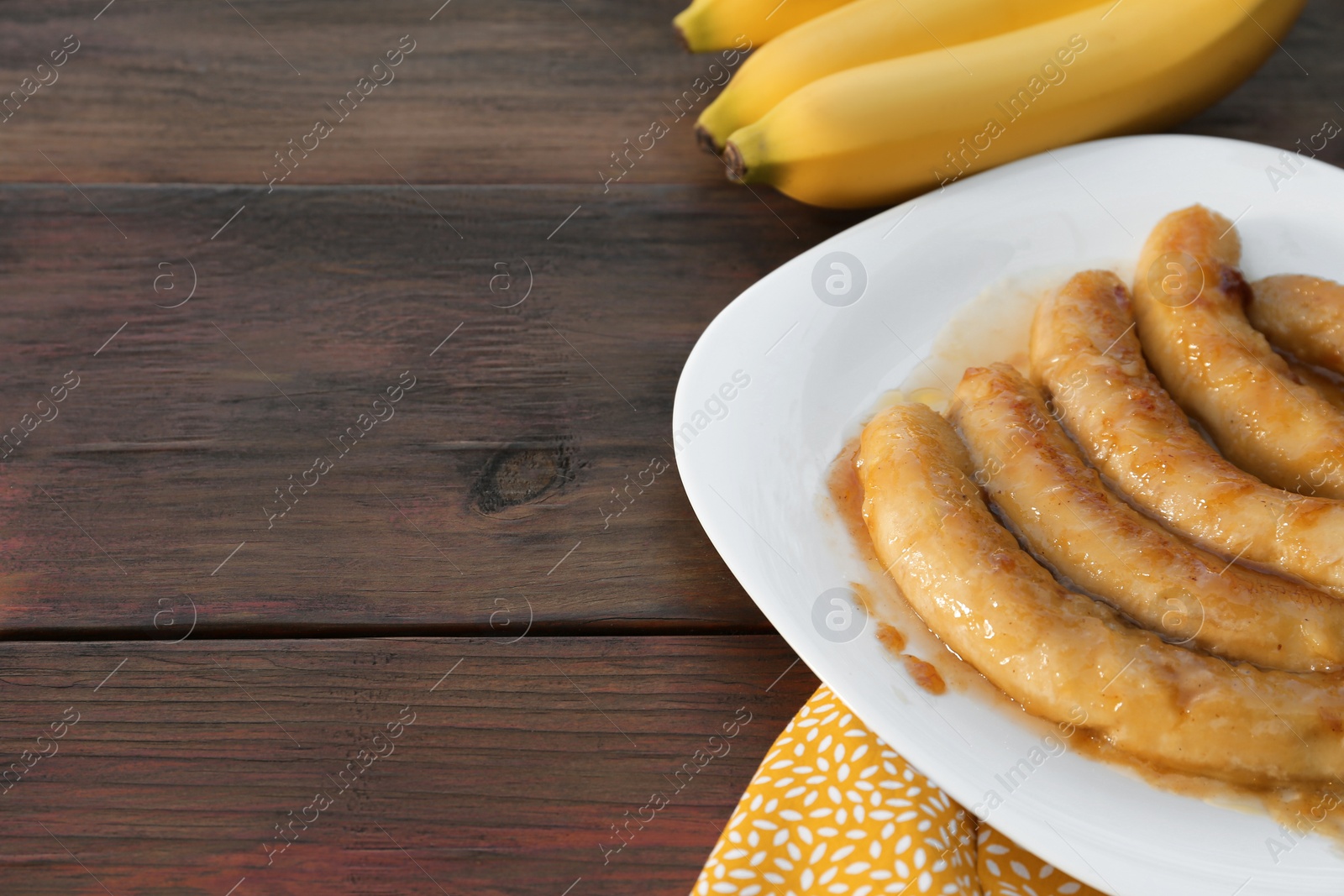 Photo of Delicious fried and fresh bananas on wooden table, closeup. Space for text