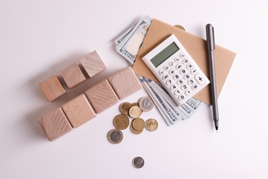 Photo of Taxes. Wooden cubes, calculator, coins and banknotes on white background, top view