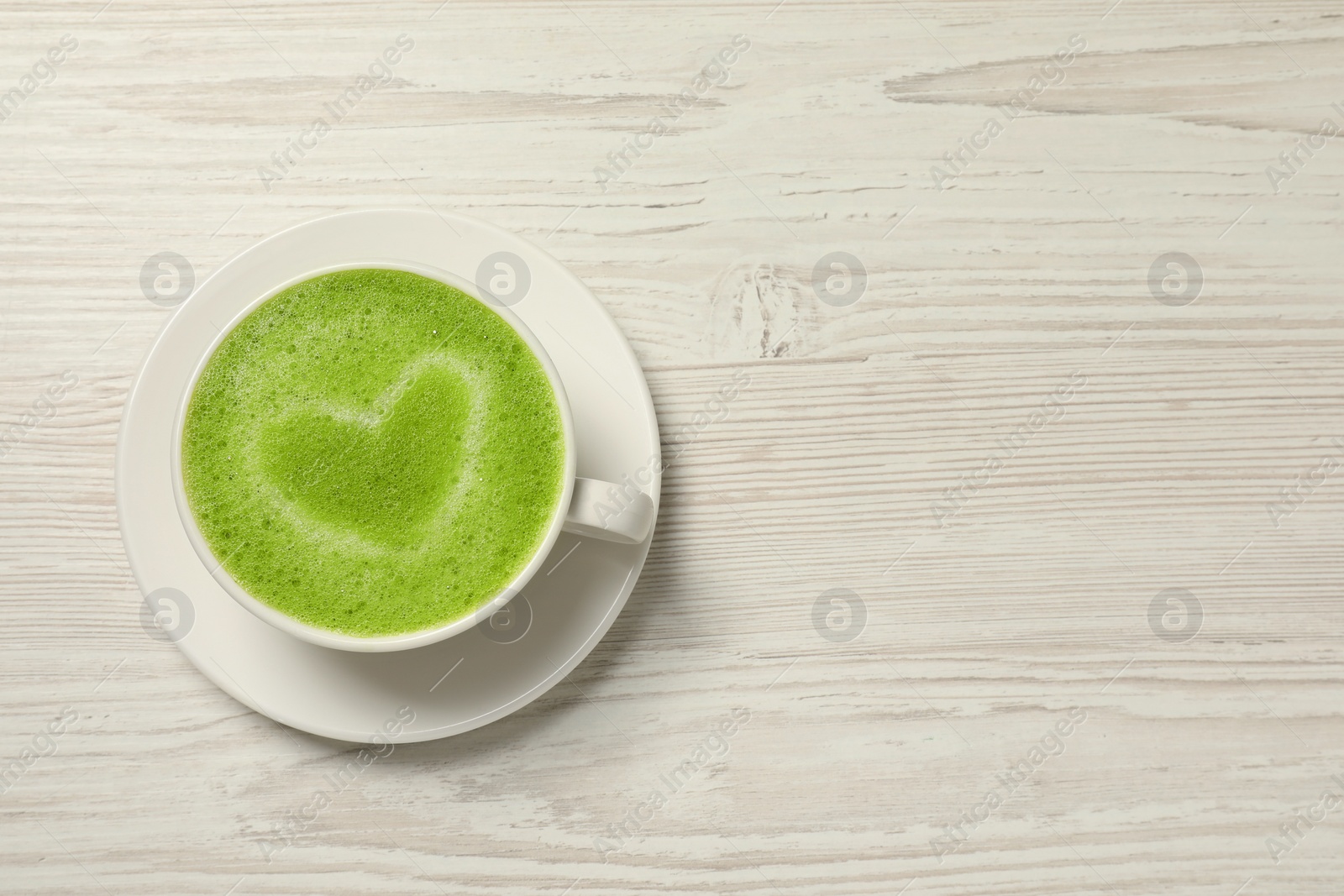 Photo of Cup of tasty matcha latte on white wooden table, top view. Space for text