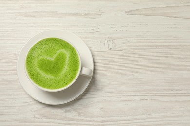 Photo of Cup of tasty matcha latte on white wooden table, top view. Space for text
