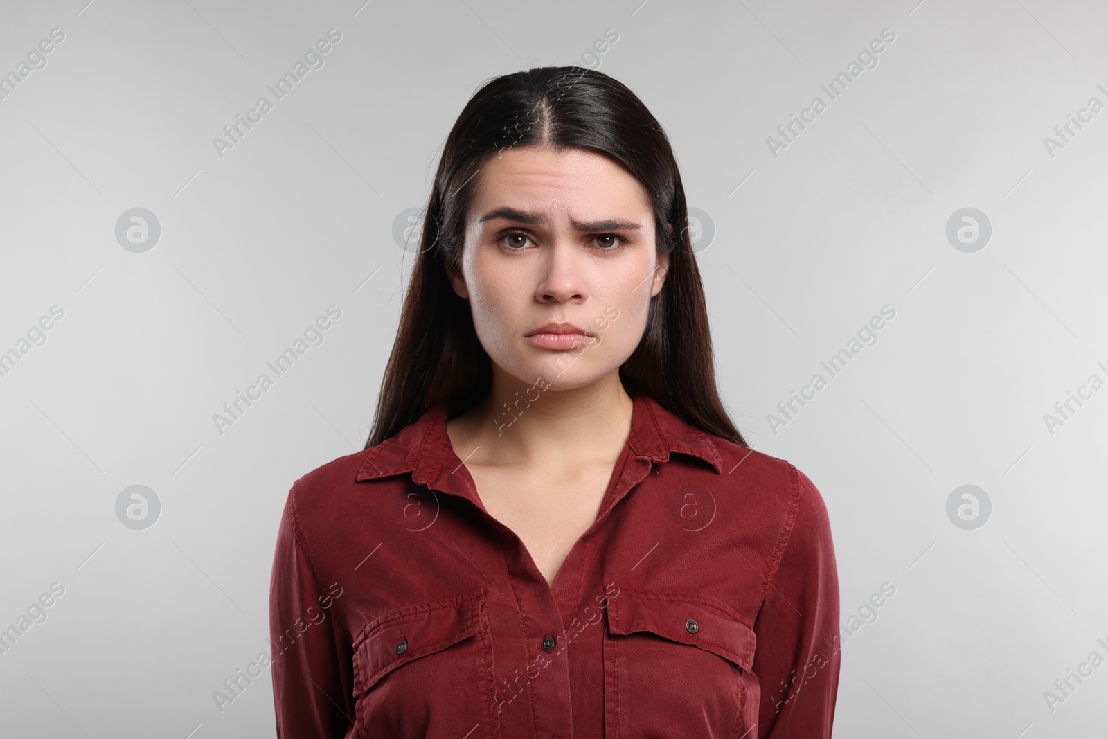 Photo of Sadness. Unhappy woman in red shirt on gray background