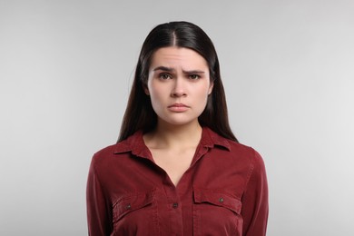 Sadness. Unhappy woman in red shirt on gray background