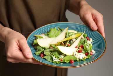 Photo of Woman holding plate with fresh pear salad, closeup