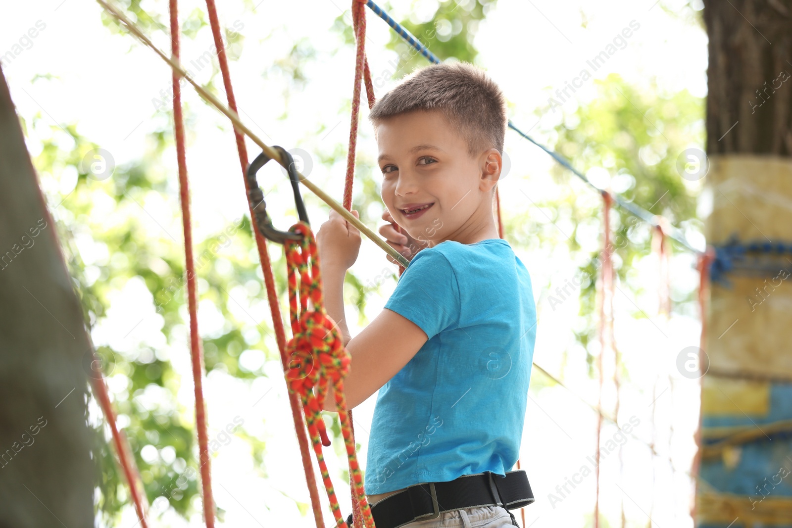 Photo of Little boy climbing in adventure park. Summer camp