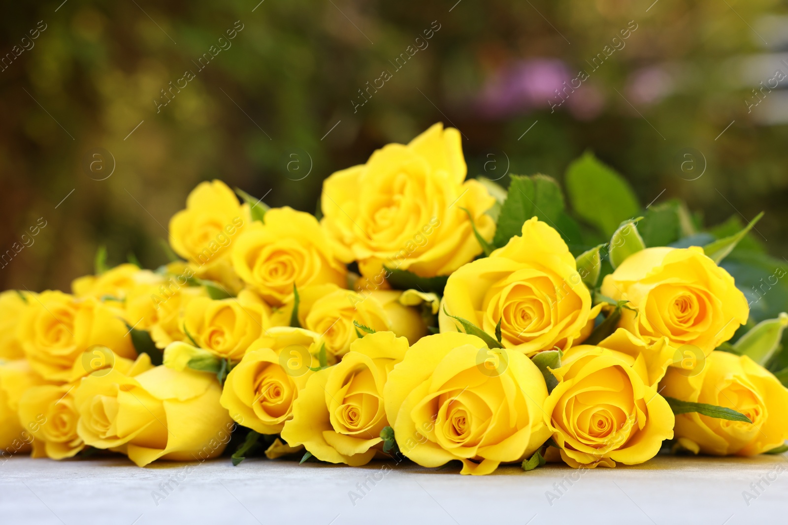 Photo of Beautiful bouquet of yellow roses on light table outdoors