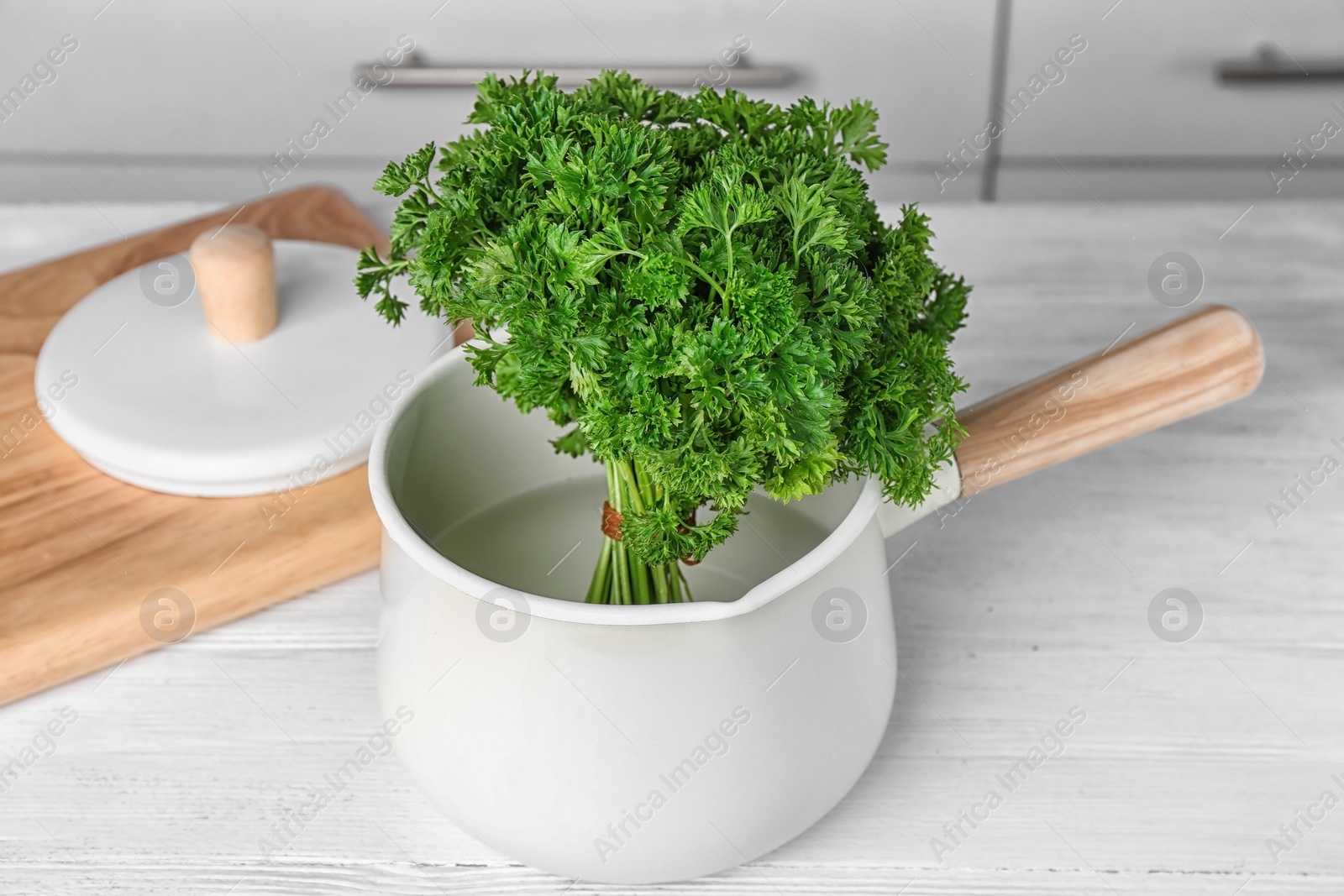 Photo of Saucepan with fresh green parsley on table