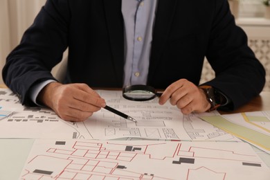 Photo of Professional cartographer working with cadastral map at table in office, closeup