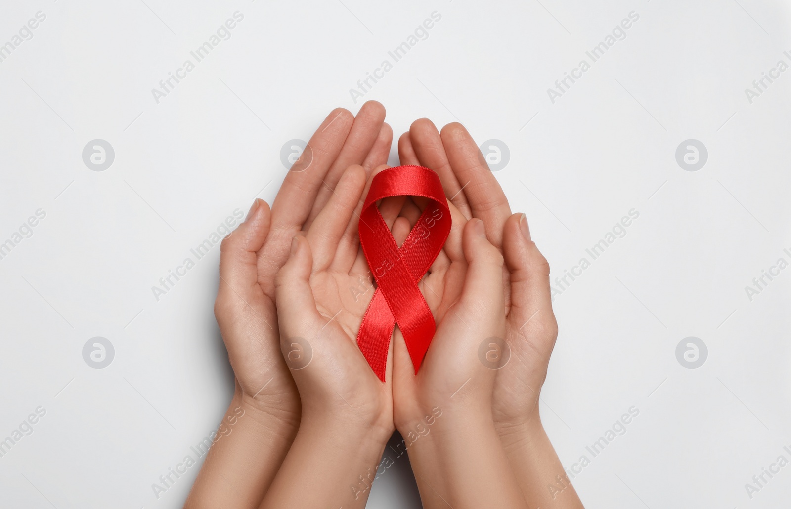 Photo of Woman and girl holding red ribbon on white background, top view. AIDS disease awareness