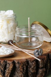 Photo of Ingredients for homemade candle on wooden stump against green background