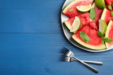 Photo of Plate with juicy watermelon and lime on blue wooden table, flat lay. Space for text