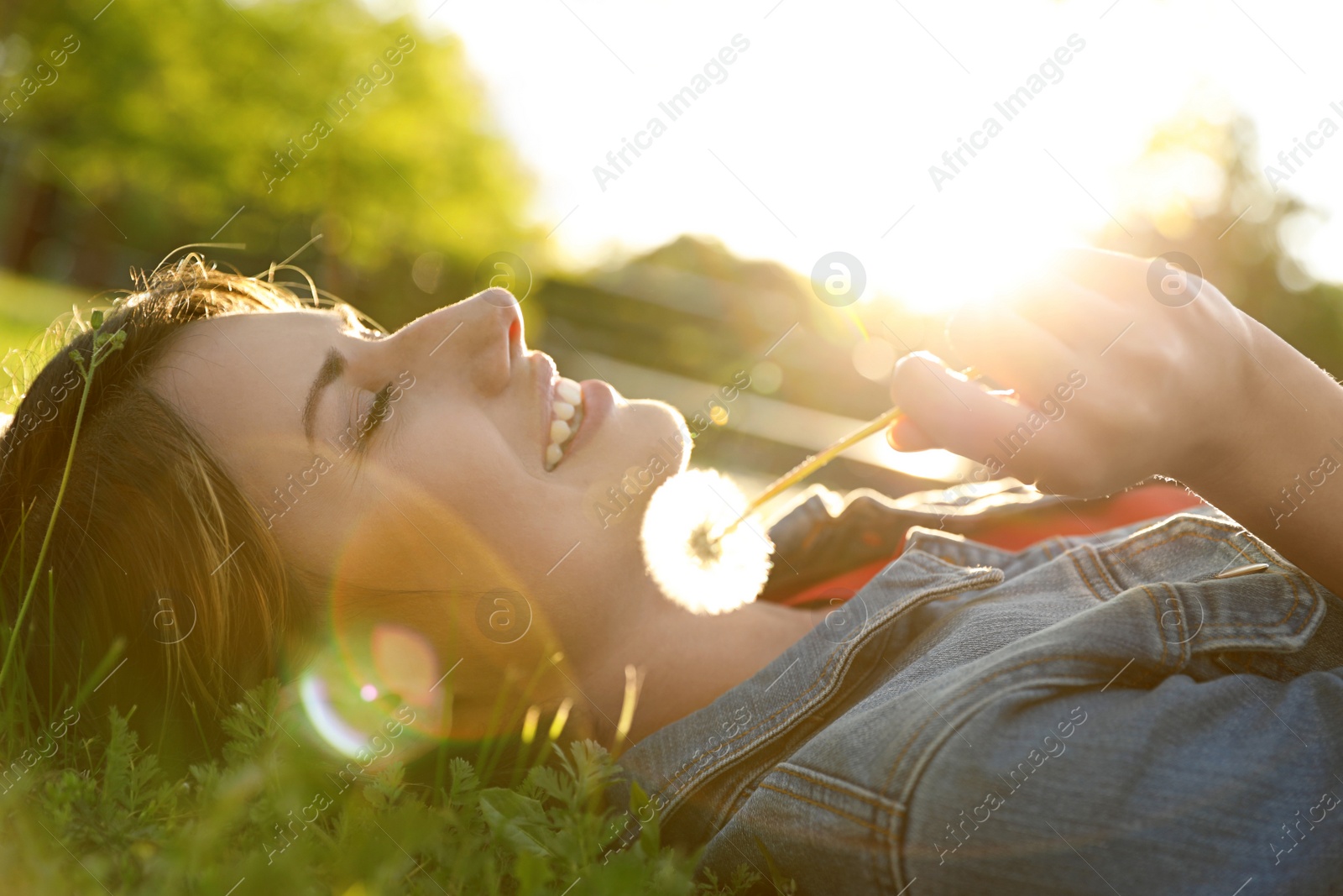 Photo of Young woman with dandelion in park on sunny day. Allergy free concept