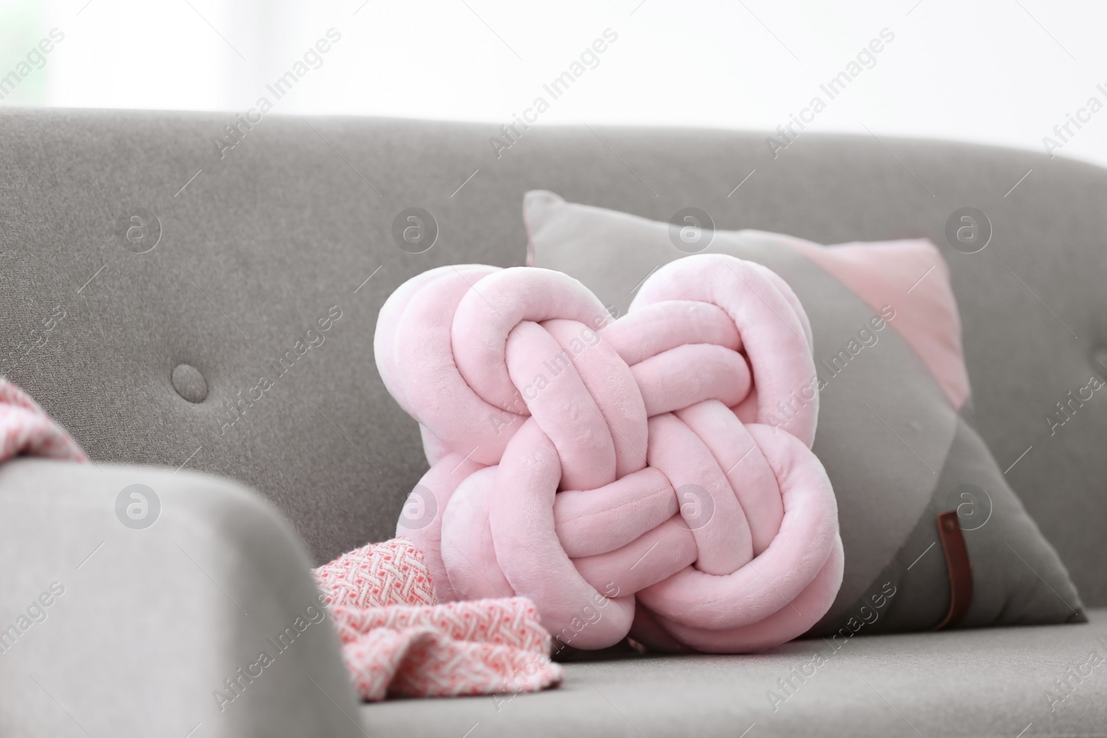 Photo of Pillows and plaid on sofa indoors. Unusual cushion design