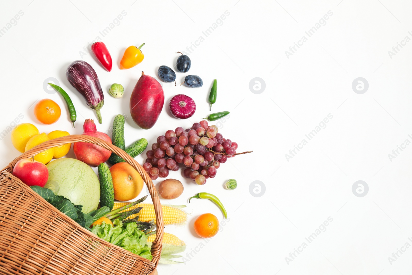 Photo of Basket with assortment of fresh organic fruits and vegetables on white background, top view