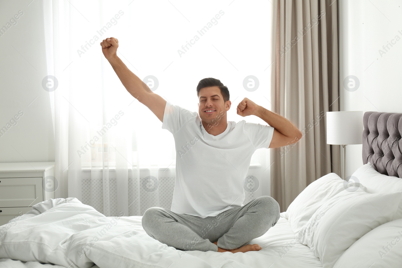 Photo of Man awakening on bed at home. Lazy morning