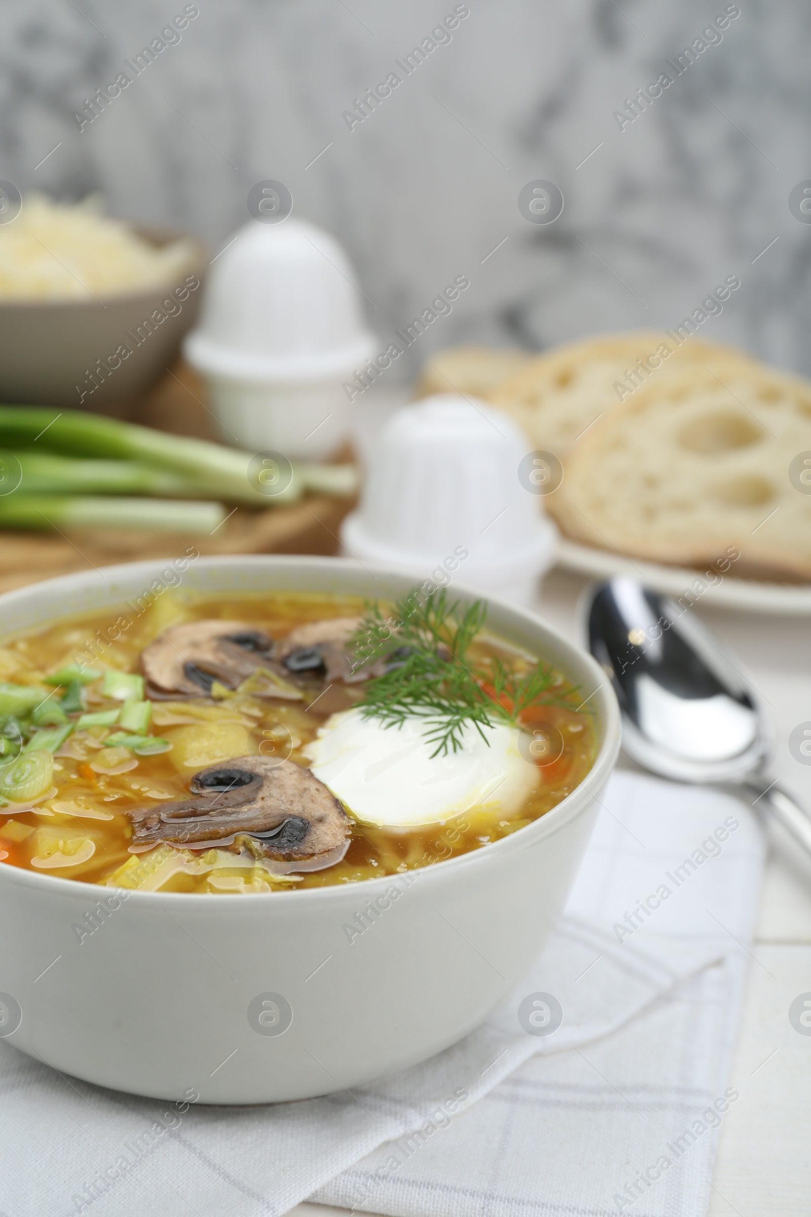 Photo of Delicious sauerkraut soup with mushrooms, dill and sour cream served on white table