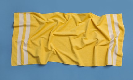 Photo of Crumpled yellow beach towel on blue background, top view