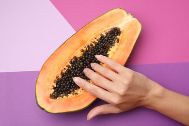 Photo of Young woman touching half of papaya on color background, top view. Sex concept