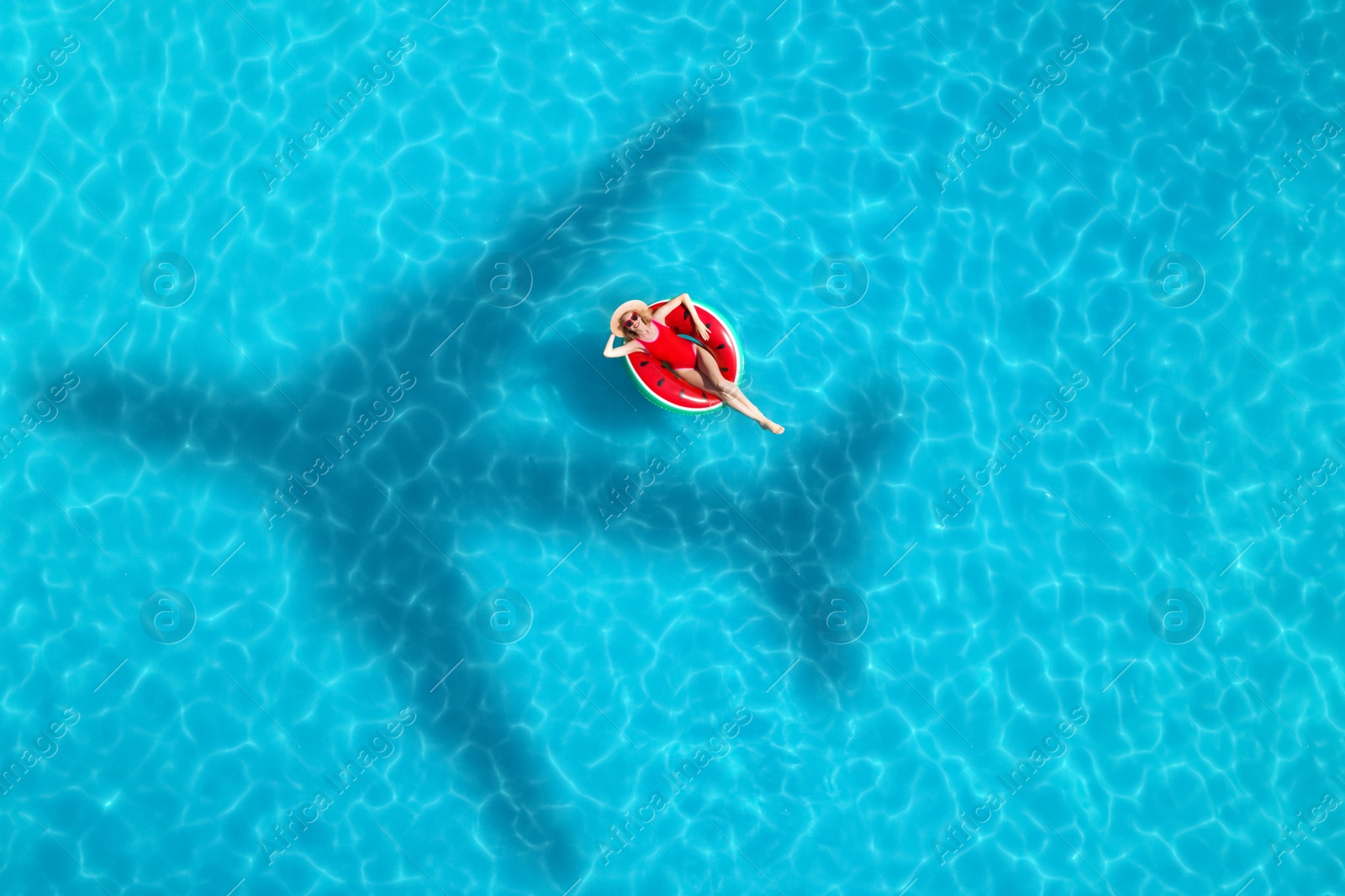 Image of Shadow of airplane and happy woman on inflatable ring in swimming pool, aerial view. Summer vacation