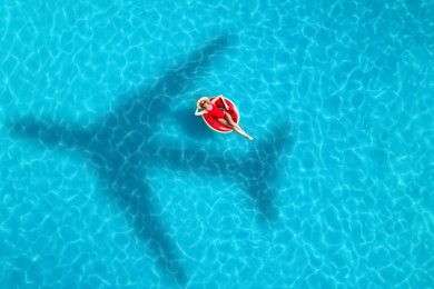 Shadow of airplane and happy woman on inflatable ring in swimming pool, aerial view. Summer vacation