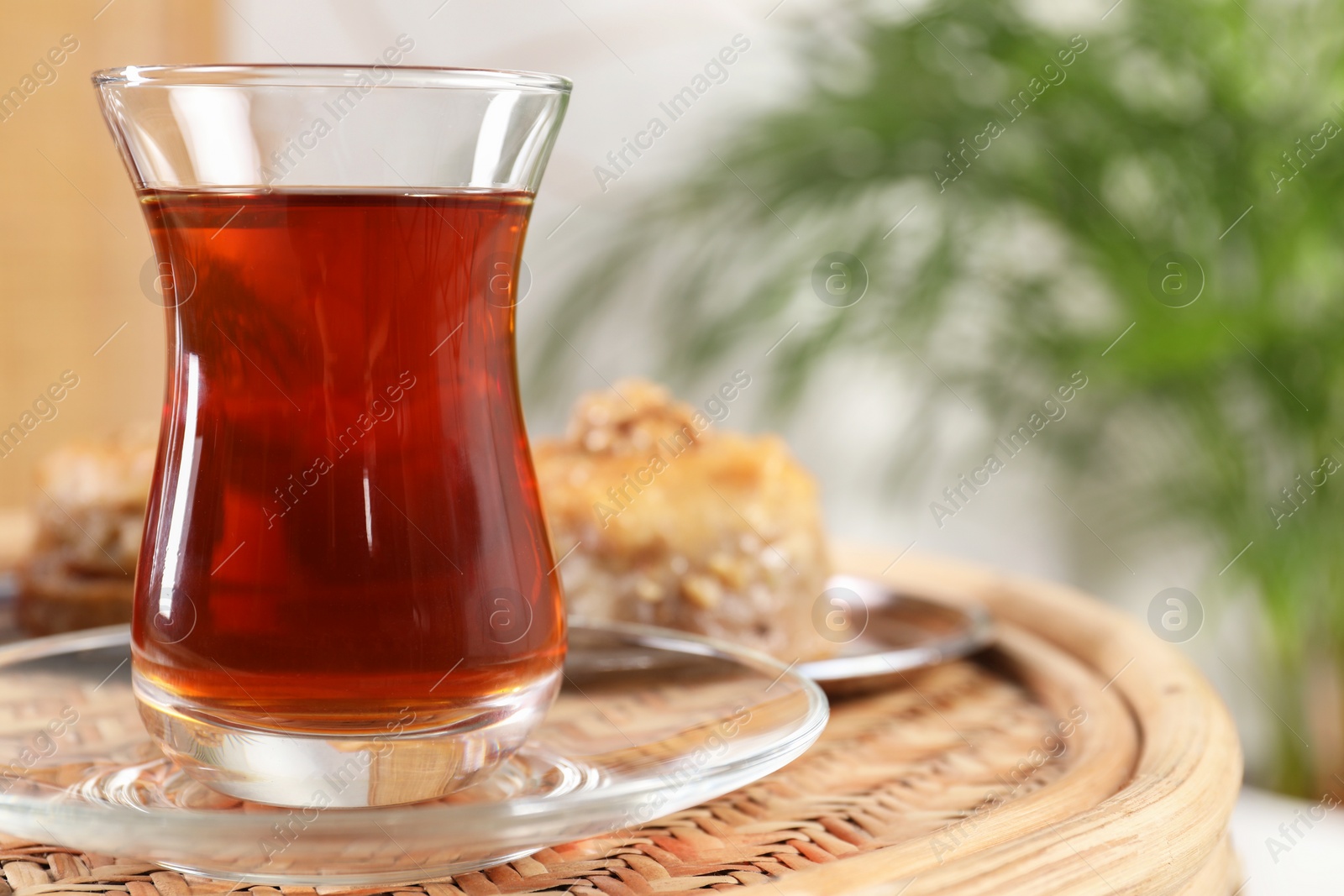 Photo of Traditional Turkish tea in glass on wicker table, closeup. Space for text