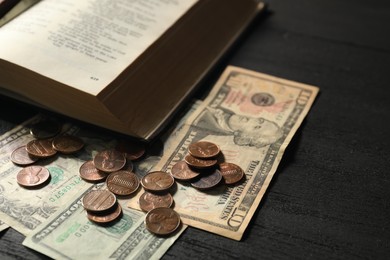 Photo of Donate and give concept. Coins, dollar banknotes and Bible on black wooden table, closeup