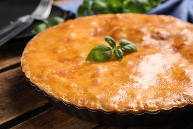 Delicious pie with meat and basil on wooden table, closeup