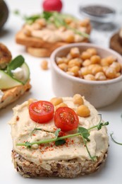 Photo of Delicious sandwiches with hummus and ingredients on white table