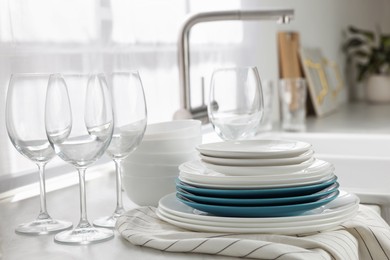 Photo of Different clean dishware and glasses on countertop near sink in kitchen