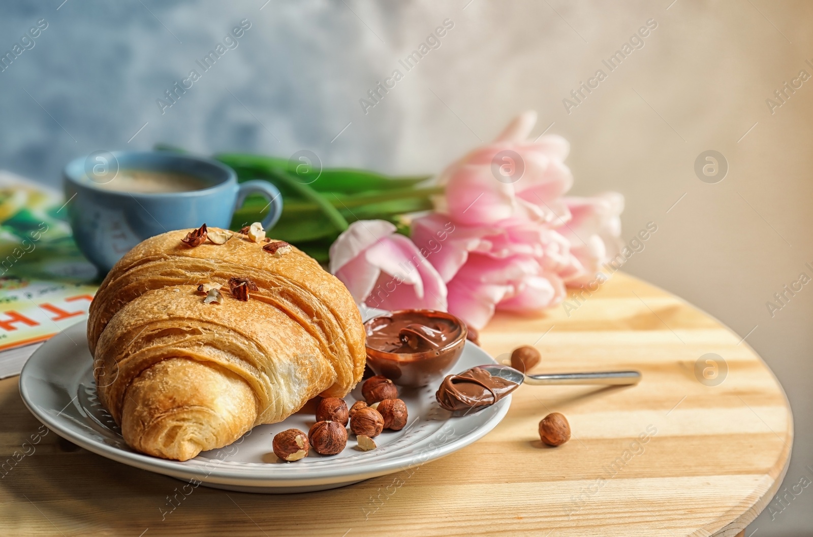 Photo of Tasty croissant with chocolate and nuts on table