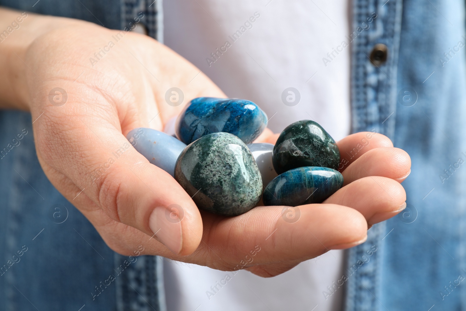 Photo of Young woman holding many beautiful gemstones, closeup