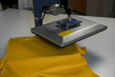 Photo of Printing logo. Heat press with t-shirt on white table, closeup