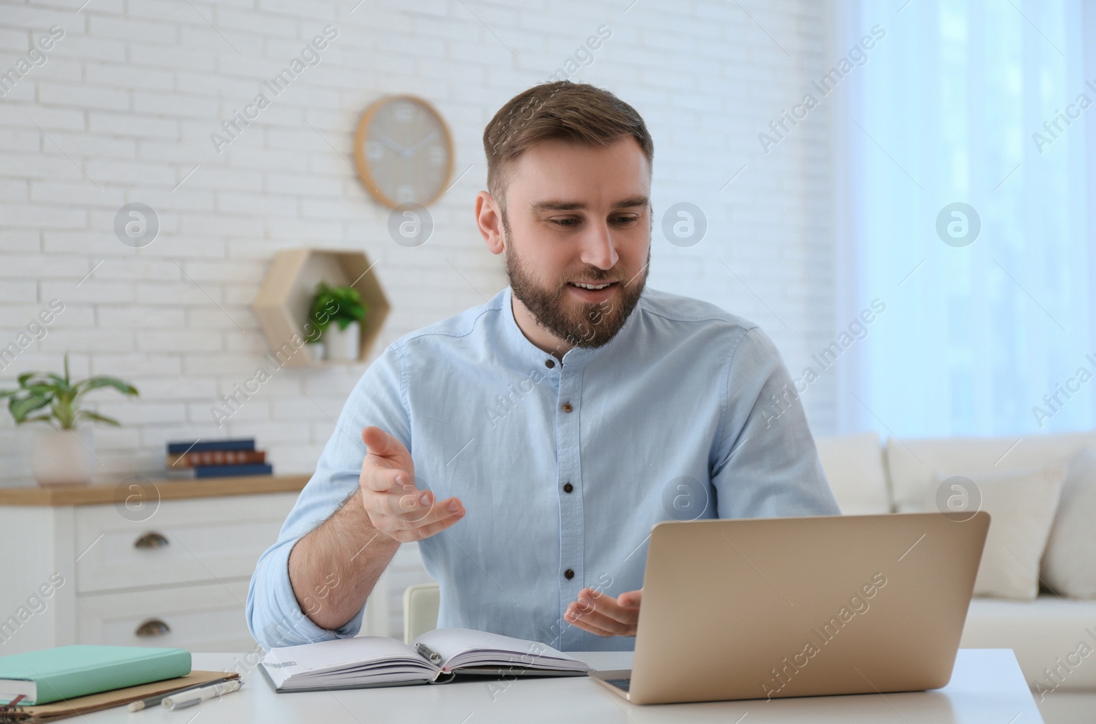 Photo of Young man watching online webinar at table indoors