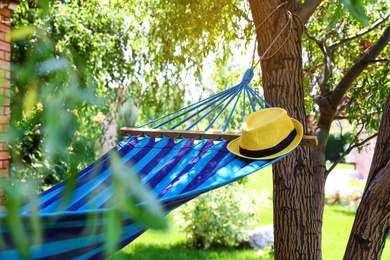 Photo of Comfortable blue hammock with hat outdoors on sunny day