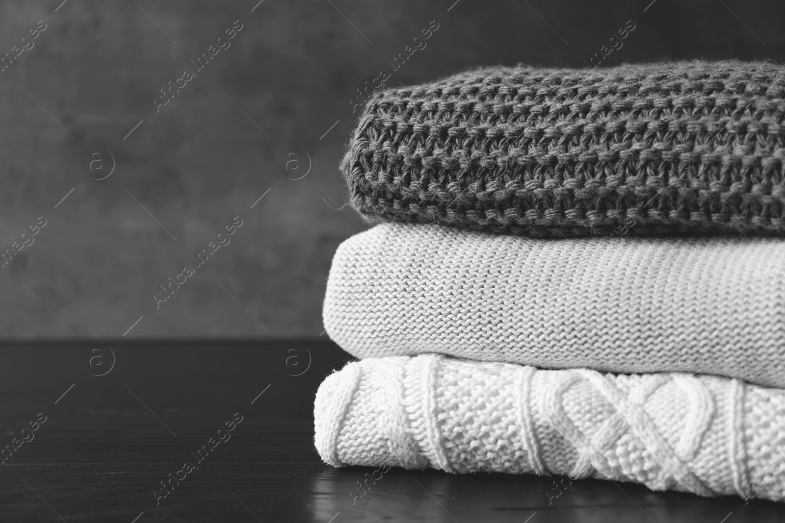 Photo of Stack of warm knitted clothes on table