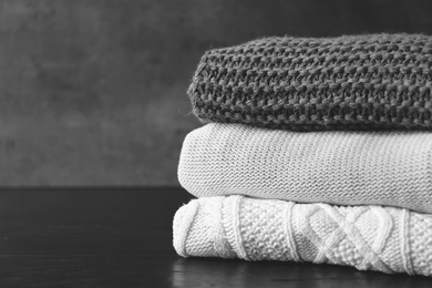 Photo of Stack of warm knitted clothes on table