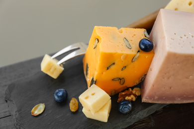 Different types of delicious cheeses on slate plate, closeup