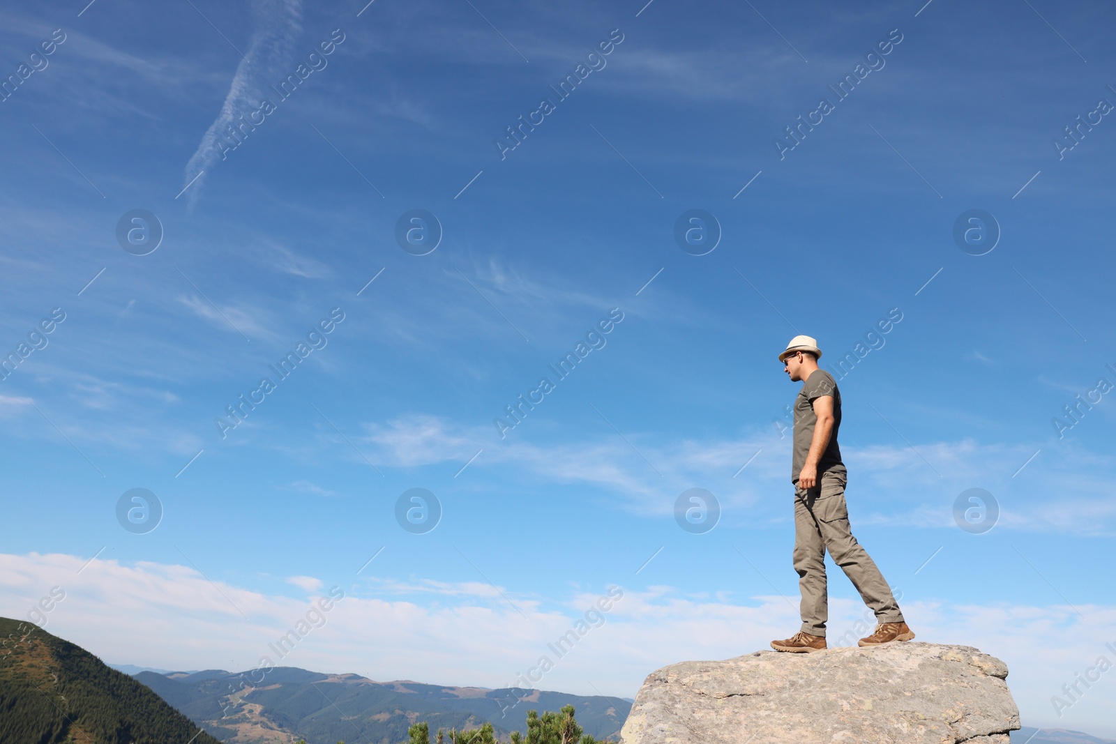 Photo of Man enjoying picturesque view on cliff in mountains. Space for text